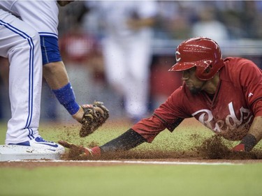 Cincinnati Reds' Billy Hamilton dives back to first ahead of the tag from Toronto Blue Jays first baseman Justin Smoak during first inning MLB exhibition action Friday, April 3, 2015, in Montreal.
