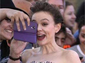 Carey Mulligan reacts as she has a picture taken with a fan upon arrival at the the World premiere of the film Far From The Madding Crowd in central London, Wednesday April 15, 2015.