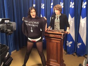 A member of FEMEN, the feminist protest group, interrupts a news conference by Quebec Culture and Communications Minister Hélène David, right, in Quebec City on Thursday.