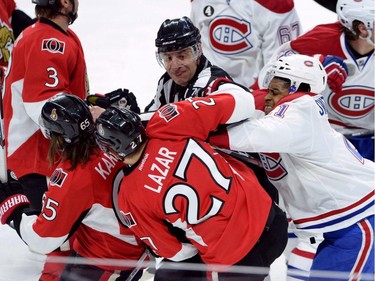 Montreal Canadiens forward Devante Smith-Pelley (21) pushes Ottawa Senators forward Curtis Lazar (27) and defenceman Erik Karlsson (65) during the first period of game 3 of first round Stanley Cup NHL playoff hockey action in Ottawa on Sunday, April 19, 2015.