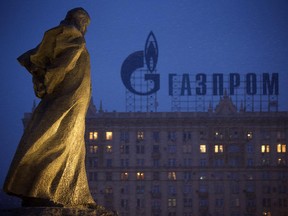 Amonument to Ukrainian poet and writer Taras Shevchenko is silhouetted against an apartment building with a sign advertising Russia's natural gas giant Gazprom.
