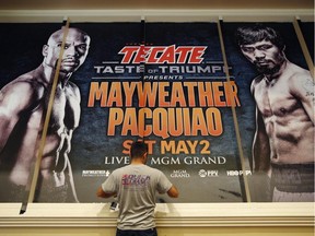 Jose Arroyo installs an advertisement for a fight between Floyd Mayweather Jr. and Manny Pacquiao at the MGM Grand, Friday, April 24, 2015, in Las Vegas. The fight is scheduled to take place May 2 at the hotel and casino.