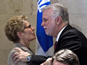 Ontario Premier Kathleen Wynne, left, and Quebec Premier Philippe Couillard, hug after they signed an agreement on the environment, Monday, April 13, 2015 at the Premier's office in Quebec City.