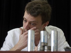 Maxence Valade sits behind CS gas grenade casings and other spent shells during a press conference in Montreal, Tuesday April 1, 2015.