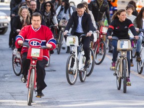 Montreal Mayor Denis Coderre, left, rides a Bixi designed by the city of Montreal as he is followed by many Quebec personalities with their own Bixi designs during an event to mark the first day of the season for the Bixi bike-sharing program outside of Montreal city hall on Wednesday.