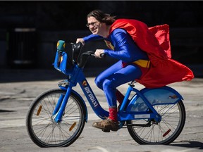 Quebec personality Jean-René Dufort (Infoman) rides a Bixi bicycle painted with his design called "Le vector BIXI écoresponsable des superhéros" during an event to mark the first day of the season for Bixi outside of Montreal city hall in Montreal on Wednesday, April 15, 2015.