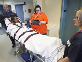 Would be patient Natasha Smith, played by Nicole Yeba, lies on stretcher while transfer nurse coordinator Lyne Mainville, centre, authorizes transport from the Montreal Children's to the new Glen Hospital, during mock move held on Tuesday.