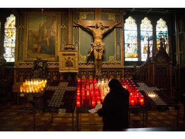 A woman lights a candle at Notre Dame Basilica as part of the Via Crucis (Way of the Cross) procession. Regular stops along the route are scheduled to give participants time to reflect and pray. Friday April 3, 2015.