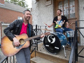 Noah Sidel, with his son Elijah on his lap, and Audiocassette bandmate Charles Houle play some music on sidel's front porch in N.D.G. on Thursday. Audiocassette will be be hosting the final event of Porchfest in N.D.G., including a charity BBQ.
