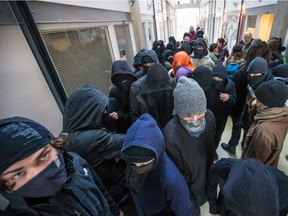 Masked student protesters participating in a student strike attempt to find university classes to at UQAM in Montreal on Tuesday, April 7, 2015.