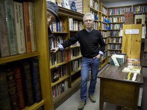 A customer peeks through a bookshelf at Bernard Wolf's Odyssey Bookstore.