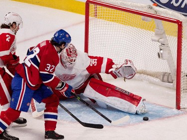 Detroit Red Wings goalie Jimmy Howard deflects a shot by Montreal Canadiens right wing Brian Flynn, centre, as Detroit Red Wings defenceman Brendan Smith tries to clear Flynn from the goal crease during NHL action at the Bell Centre in Montreal on Thursday April 9, 2015.