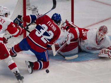 Detroit Red Wings left wing Drew Miller, left, knocks Montreal Canadiens right wing Brian Flynn to the ice as Detroit Red Wings goalie Jimmy Howard reaches for the loose puck during NHL action at the Bell Centre in Montreal on Thursday April 9, 2015.