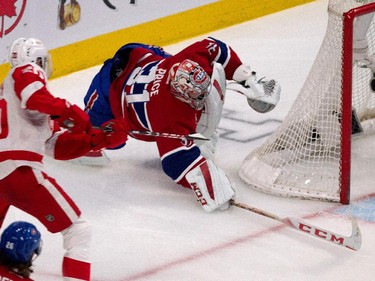 Montreal Canadiens goalie Carey Price dives to deflect the puck as Detroit Red Wings left wing Drew Miller, left, tries to score while Price was caught behind the net during NHL action at the Bell Centre in Montreal on Thursday April 9, 2015.