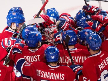 Montreal Canadiens goalie Carey Price, centre, is swarmed by his teammates after he set the new club record with 43 regular season wins. The Canadiens beat the Detroit Red Wings 4-3 in overtime at the Bell Centre in Montreal on Thursday April 9, 2015.
