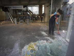 UQAM employees clean up broken glass after a night of protests at the J.A. de Seve building part of UQAM in Montreal, on Thursday, April 9, 2015.