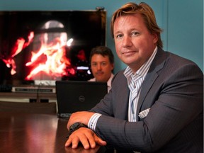 Eric Boyko, right, and Mathieu Peloquin display the fire log TV signal feed in the offices of Stingray Digital in Montreal on Monday July 7, 2014.