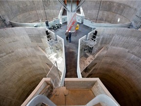 Workers are dwarfed by four massive sewage tanks at the Montreal sewage treatment facility.