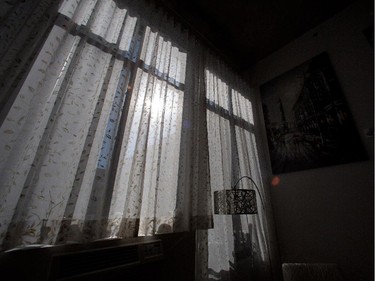 The sun breaks through the curtains on a floor to ceiling wall of windows.