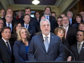Quebec Premier Philippe Couillard addresses a news conference marking his first year of government, Tuesday, April 7, 2015 in Quebec City. Members of his cabinet stand behind.