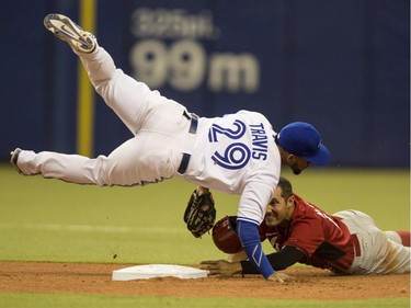 Toronto Blue Jays third baseman Jake Fox falls over Cincinnati Reds' Ben Klimesh after throwing to first to complete the double play during sixth inning MLB exhibition action Friday, April 3, 2015, in Montreal.