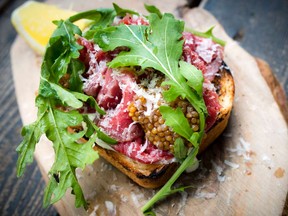 Chef Marc Doiron's beef carpaccio crostini dish with mustard seed. He seasons with salt, lemon juice, a little arugula and garnishes with parmesan shavings.