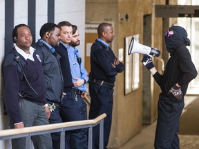 A masked protester uses a blow horn to disturb security guards and the classroom they are guarding against student protesters at Pavillon J.-A.-DeSève of L'Université du Québec à Montréal (UQAM) in Montreal on Monday, April 13, 2015.