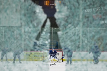 Tampa Bay Lightning goalie Ben Bishop is seen through a pane of glass broken by a shot from teammate Braydon Coburn during practice at the Ice Sports Forum in Tampa, Fla., on May 11, 2015.