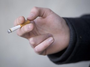 A smoker is seen holding his cigarette during a smoke break outside a building in North Vancouver, B.C. Monday, Jan. 20, 2014.