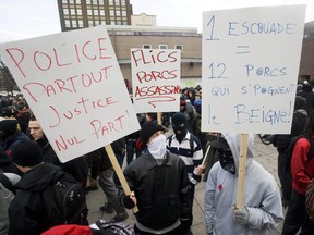 MONTREAL, MARCH 15, 2012: Masked protestors hold up signs during an anti-police brutality demonstration in Montreal, Thursday, March 15, 2012. [THE GAZETTE/Graham Hughes]