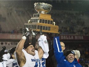 Montreal Carabins' Byron Archambault and head coach Danny Maciocia hoist the Vanier Cup after beating the McMaster Marauders in the CIS football final in Montreal Saturday, November 29, 2014.