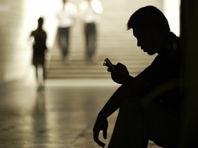 A man sits alone, checking his phone.