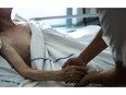 A file picture taken on July 22, 2013 shows a nurse holding the hand of an elderly patient at the palliative care unit of the Argenteuil hospital, outside Paris.