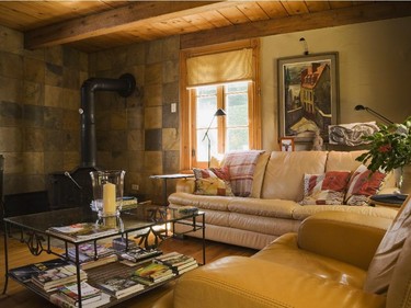 In the family room on the ground floor, slate tiles behind the wood stove complement the patchwork cushions on the soft and comfortable leather sofas.