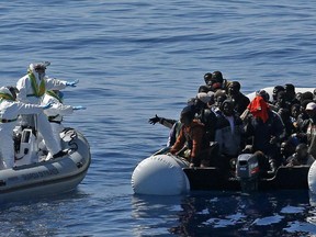 In this photo made available Thursday, April 23, 2015, an Italian Financial Police rescue unit approaches an inflatable dinghy crowded with migrants off the Libyan coast, in the Mediterranean Sea, Wednesday, April 22, 2015.
