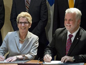 Ontario Premier Kathleen Wynne, left, and Quebec Premier Philippe Couillard, sign an agreement on the environment April 13, 2015, in Quebec City.