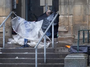 A man takes shelter from the rain in a makeshift tent in downtown Montreal, Tuesday April 8, 2014.