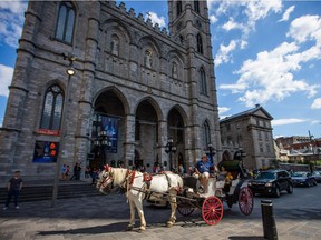 MONTREAL, QUE.: JULY 30, 2013 -- A horse carriage with tourists pass in front of the Notre-Dame Cathedral in Old Port in Montreal on Tuesday, July 30, 2013.