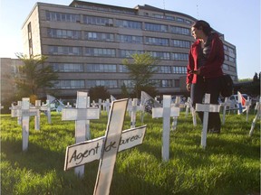 A woman walks through crosses representing potential job losses outside the Commission scolaire de Montréal offices in Montreal Wednesday, May 13, 2015. The CSDM was to vote tonight on cutting nearly 200 jobs (170 student support jobs, and 20 or so administration jobs). Unions representing school-board workers held a demo beforehand.