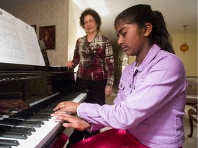 MONTREAL, QUE.: MAY 14, 2015 -- Jean Jaslin Jesuthasan (right) at the home of her music teacher Adrienne Fischer (behind) in the Dollard-des-Ormeaux area of Montreal Thursday, May 14, 2015. The  11- year-old scored a 94 per cent on her Grade 1 Royal Conservatory of Music exam and traveled to Toronto to receive a gold medal for the highest score in 2014, for her grade, in the province. Her family can't afford to pay for her Grade 2 exam, so her teacher Adrienne Fischer is designing a "mock" Grade 2 exam for her to take.  (John Kenney / MONTREAL GAZETTE)