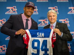 Newly signed player for the Montreal Alouettes Michael Sam, left, and Alouettes general manager Jim Popp, right, pose for photographs at a press conference in Montreal on Tuesday, May 26, 2015. Sam, who is the first openly gay player in football, signed a two year contract with the Alouettes.