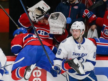 Canadiens right wing Brandon Prust, left, falls onto Canadiens goalie Dustin Tokarski, centre, in the player's bench after colliding with Tampa Bay Lightning right wing Nikita Kucherov, right, during the first period of game two of their NHL eastern conference semi-final hockey series at the Bell Centre in Montreal on Sunday, May 3, 2015.