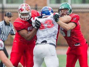 Defensive lineman Mathieu Dupuis of Université de Montréal and Team East is blocked by offensive linemen Jamal Campbell (left) and Drew Digout of Team West at the CIS East-West Bowl at Percival Molson stadium in Montreal Saturday, May 9, 2015. Top university players in country took part in the game which was won by the team from the east.