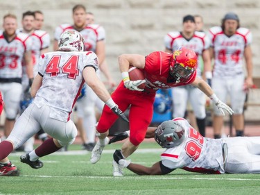 MONTREAL, QUE.: MAY 9, 2015 --Running back Mercer Timmins (centre) of the University of Calgary is tripped up by defensive lineman Jordan Dablé (bottom right) of Team East at the CIS East-West Bowl at Percival Molson stadium in Montreal Saturday, May 9, 2015. On the left is defensive lineman Lucas Cristovao of St. Mary's. Top university players in country took part in the game which was won by the team from the east. (John Kenney / MONTREAL GAZETTE)