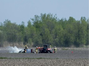 Firefighters work to extinguish a fire of a small airplane that crashed in a farmer's field in St-Lazare on May 14, 2015.