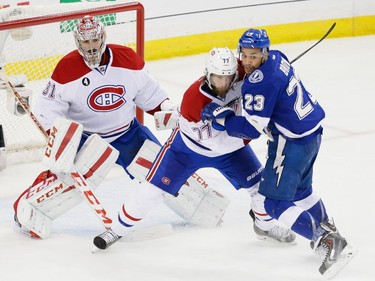 Montreal Canadiens defenceman Tom Gilbert, centre, and Tampa Bay Lightning right wing J.T. Brown, right, battle for space as Montreal Canadiens goalie Carey Price, left, looks on during the second period of game four of their NHL eastern conference semi-final hockey series at Amalie Arena in Tampa on Thursday, May 7, 2015.