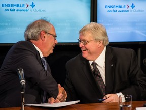 Louis Godin, president of the Fédération des médecins omnipraticiens du Québec, left, shakes hands with Quebec Health Minister Gaétan Barrette, right, after announcing that the province’s family physicians and the Quebec government reached an agreement to avert a proposed quota system for family physicians as would be imposed by Bill 20, in Montreal on Monday, May 25, 2015.