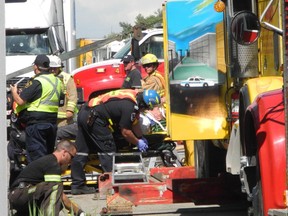 Emergency response personnel work on a passenger from the Megabus that collided into trees on the north side of the westbound lanes of Hwy. 401 after striking a tractor-trailer about two kilometres east of Lancaster, Ont. on Tuesday June 23, 2015.