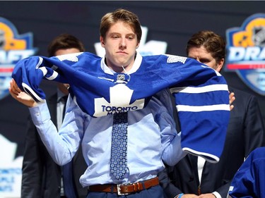 Mitchell Marner puts on his jersey after being selected fourth overall by the Toronto Maple Leafs in the first round of the 2015 NHL Draft on June 26, 2015 in Sunrise, Florida.