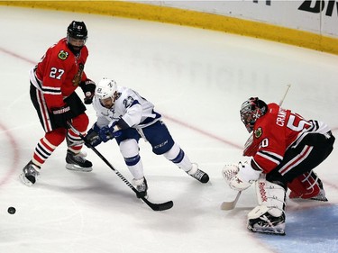 Johnny Oduya #27 and Corey Crawford #50 of the Chicago Blackhawks defend against J.T. Brown #23 of the Tampa Bay Lightning in the first period during Game Four of the 2015 NHL Stanley Cup Final at the United Center on June 10, 2015 in Chicago, Illinois.